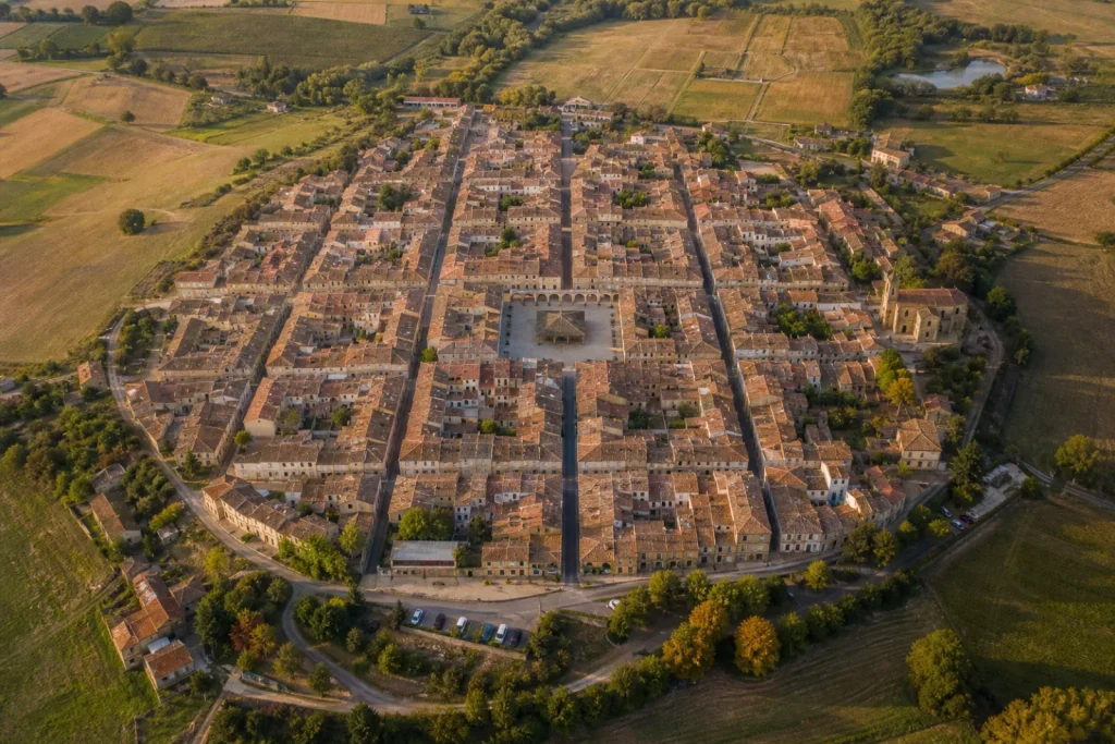 Vue aérienne d'une bastide médiévale avec son plan en damier et sa place centrale à arcades.